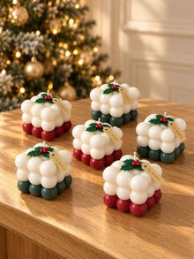 Cubos navideños de La Marie en rojo y verde, con acebo, sobre una mesa de madera junto al árbol de Navidad