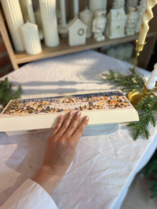 Caja de Luz cerrada con su cubierta ilustrada sobre una mesa de Navidad