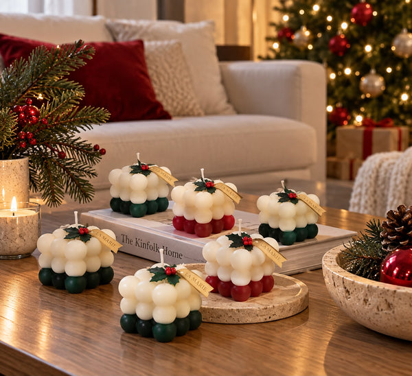 Cubos navideños de La Marie en rojo y verde sobre una mesa de centro, junto a ramas de pino, en una sala decorada para Navidad