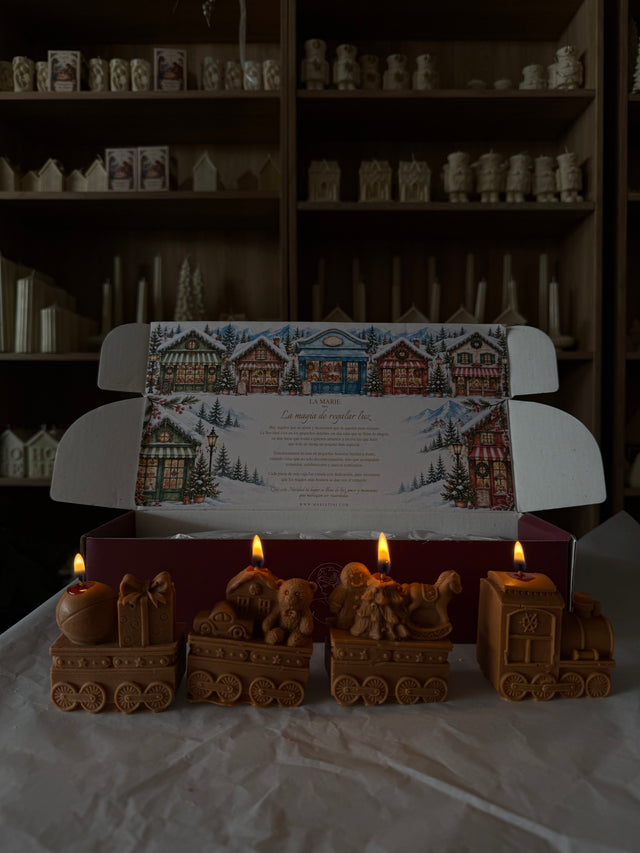 Tren Polar color caramelo frente a su caja abierta con ilustración de pueblo navideño
